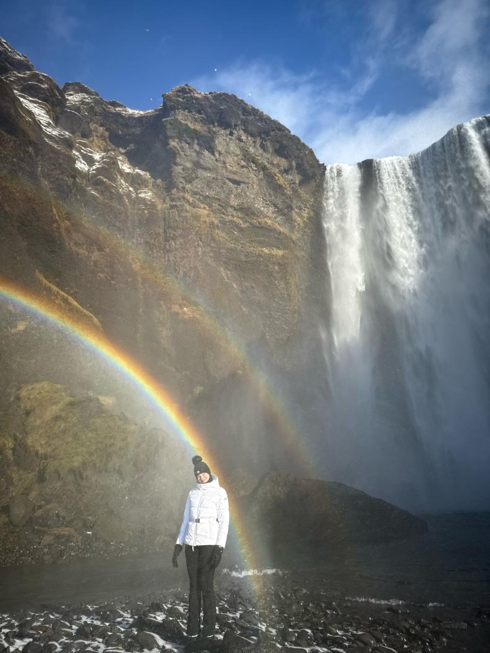 Portrait beside a waterfall and rainbow